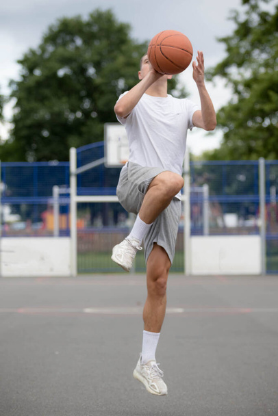A Nineteen Year Old Teenage Boy Shooting A Hoop in A Basketball Court in A Public Park - Foto, Bild