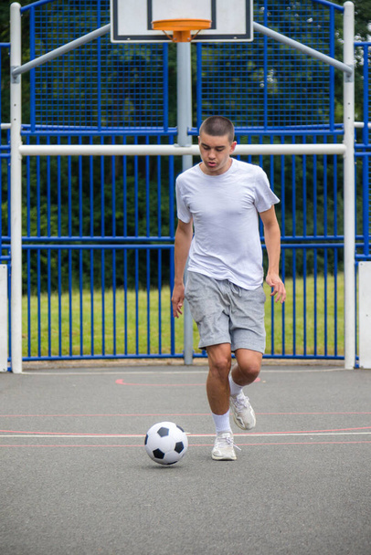 A Nineteen Year Old Teenage Boy Playing Football in A Public Park - 写真・画像