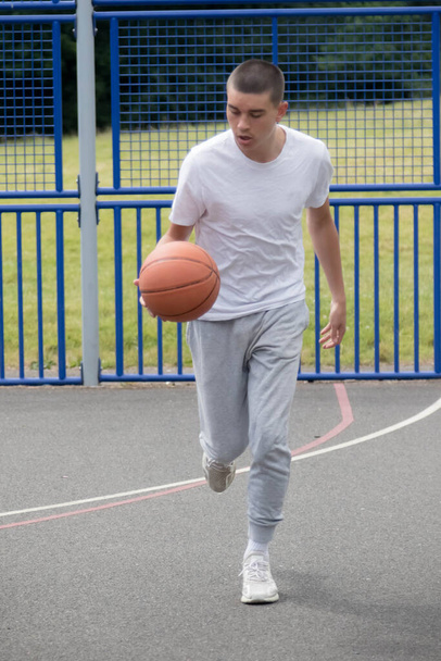 A Nineteen Year Old Teenage Boy Playing Basketball in A Public Park - Фото, изображение