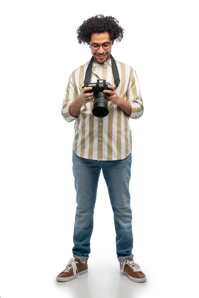 Fotografie, Beruf und Menschen und Konzept - glücklich lächelnder Mann oder Fotograf in Brille mit Digitalkamera vor weißem Hintergrund - Foto, Bild
