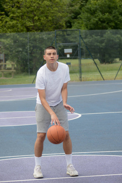 A Nineteen Year Old Teenage Boy Shooting A Hoop in A Basketball Court in A Public Park - Fotoğraf, Görsel