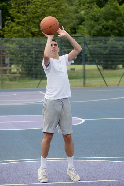 A Nineteen Year Old Teenage Boy Shooting A Hoop in A Basketball Court in A Public Park - Foto, imagen
