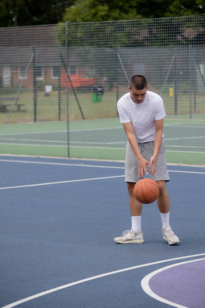 A Nineteen Year Old Teenage Boy Playing Basketball in A Public Park - Фото, зображення