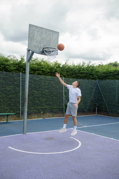 A Nineteen Year Old Teenage Boy Shooting A Hoop in A Basketball Court in A Public Park - Φωτογραφία, εικόνα