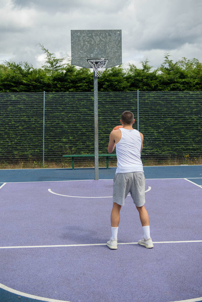 A Nineteen Year Old Teenage Boy Shooting A Hoop in A Basketball Court in A Public Park - Fotografie, Obrázek