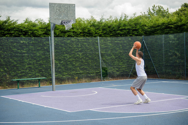 A Nineteen Year Old Teenage Boy Shooting A Hoop in A Basketball Court in A Public Park - Photo, Image