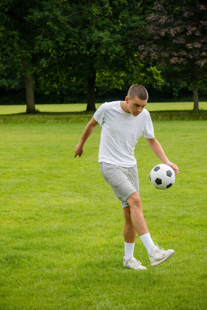 A Nineteen Year Old Teenage Boy Playing Football in A Public Park - Foto, Imagen