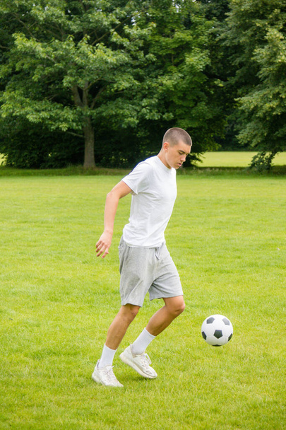 A Nineteen Year Old Teenage Boy Playing Football in A Public Park - Valokuva, kuva