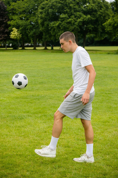 A Nineteen Year Old Teenage Boy Playing Football in A Public Park - Фото, изображение