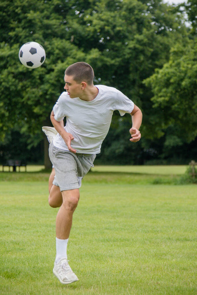 A Nineteen Year Old Teenage Boy Playing Football in A Public Park - Foto, afbeelding
