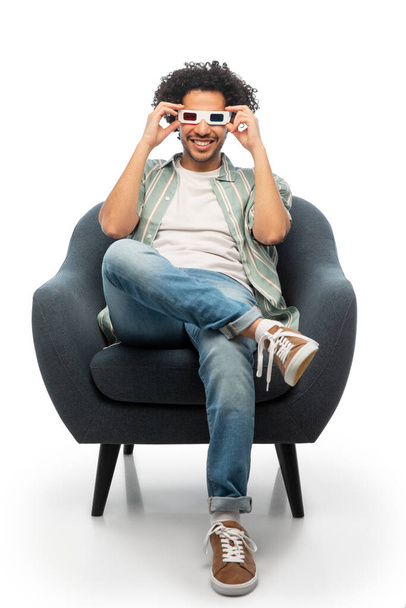 cinema, leisure and entertainment concept - happy smiling young man in 3d glasses watching movie sitting in chair over white background - Photo, image