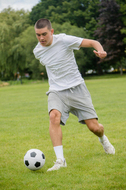 A Nineteen Year Old Teenage Boy Playing Football in A Public Park - Foto, immagini