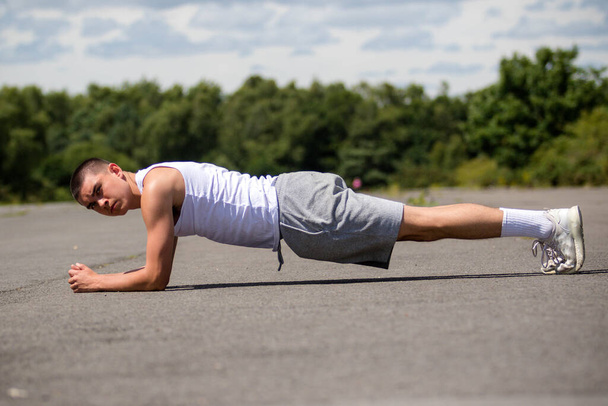 A Nineteen Year Old Teenage Boy Doing The Plank In A Public Park - Foto, Imagen