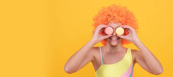 yummy. confectionery. macaroon cookie. happy childhood. birthday party. funny kid in clown wig hold french macaron. child wear swimsuit. teen dental care. girl with orange hair. summer fun. - Photo, Image