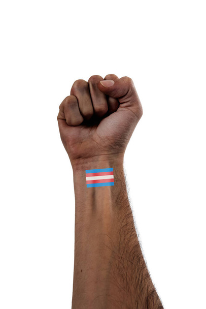 Belle et stylisée main et bras de personne afro-américaine avec poing levé et un petit tatouage de drapeau transgenre de fierté sur fond 100 % blanc - Photo, image
