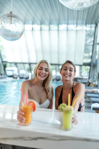 Women friends drink, cocktail mojito on pool bar, wear bikini luxury hotel near beach on tropical island relax - Foto, Imagem