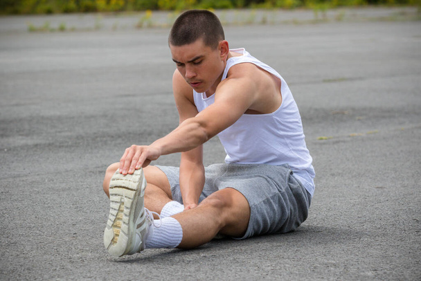 A Nineteen Year Old Teenage Boy Stretching In A Public Park - 写真・画像