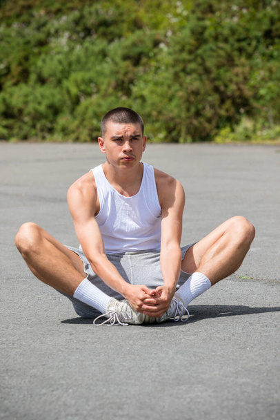 A Nineteen Year Old Teenage Boy Stretching In A Public Park - Photo, image