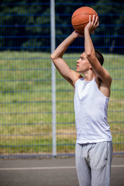 A Nineteen Year Old Teenage Boy Shooting A Hoop in A Basketball Court in A Public Park - Фото, зображення