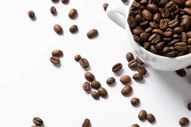 Image of pill of a coffee beans and cup of coffee beans on white background. Coffee, refreshment and beverages. - Photo, image
