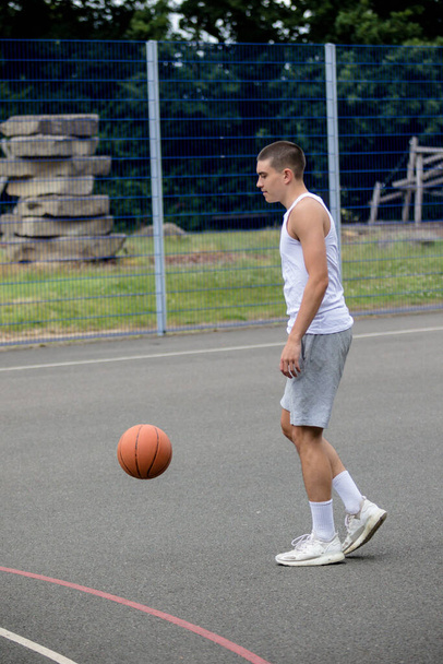 A Nineteen Year Old Teenage Boy Playing Basketball in A Public Park - 写真・画像