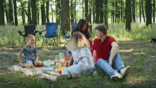 felice compagnia, mamma, papà, figlio, figlia e i loro amici stanno facendo un picnic nella foresta. famiglia campeggio in summer.resting con tenda nel parco della città foresta - Filmati, video