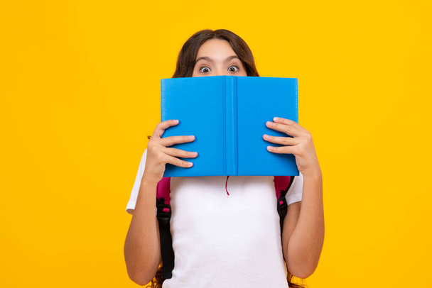 Szkolna nastolatka z plecakiem torby szkolnej trzymać książkę na żółtym izolowanym tle studio. Koncepcja szkoły i edukacji dzieci - Zdjęcie, obraz