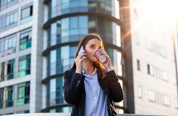 Ügyvéd üzletasszony profi sétál a szabadban beszél mobilon okos telefon iszik kávét eldobható papír pohár. Üzletasszony a mobilján. - Fotó, kép