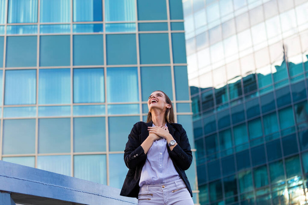 businesswoman in a business suit, exulted by happiness after finishing the deal, in the background skyscrapers. Concept of: business, technology, economy and work and success. - 写真・画像