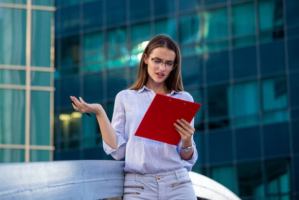 Executive business woman with clipboard against the urban background - Photo, Image