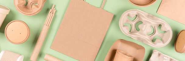 Επίπεδη lay banner φόντο με οικολογικά επιτραπέζια σκεύη, σκεύη από χαρτί μιας χρήσης και χάρτινα σκεύη που πάνω από ανοιχτό πράσινο φόντο. Έννοια βιώσιμης συσκευασίας τροφίμων - Φωτογραφία, εικόνα