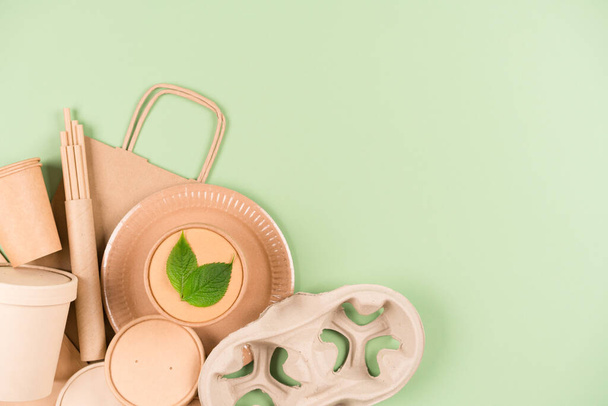 Eco paper utensils and disposable tableware set, food containers and paper cups over light green background with copy space. Sustainable food packaging concept - Foto, imagen