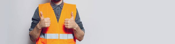 Young construction worker on white showing thumbs up. Panoramic banner. - Zdjęcie, obraz