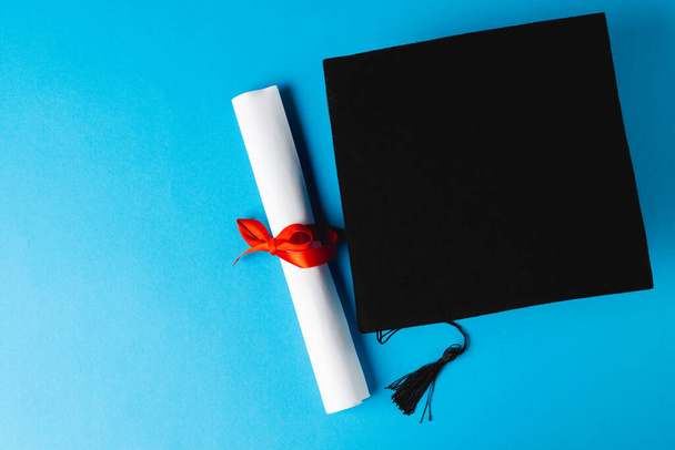 Зображення випускного капелюха та диплома на синій поверхні. Школа, навчання, освіта та концепція випуску
. - Фото, зображення