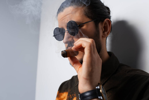 Close-up studio ritratto di un giovane uomo con un sigaro su sfondo bianco. - Foto, immagini