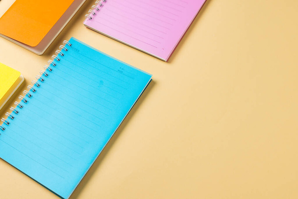 Composition of colorful notebooks lying on yellow surface with copy space. School equipment, tools and creativity concept. - 写真・画像