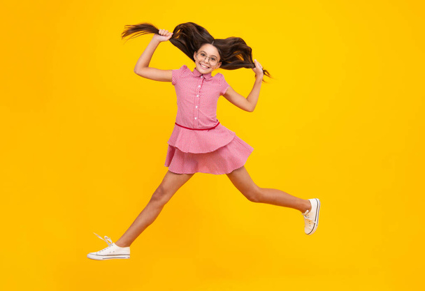 Happiness, activity and child. Teenager girl jumping on isolated background. Full length, energetic little girl jumping in air, child flying up, crazy and overjoyed. Teenager with movement hair - Foto, afbeelding