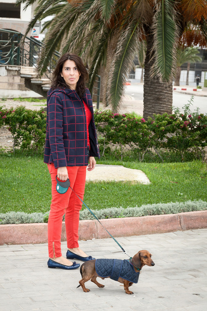 Women walking around town with dachshund dog - Фото, изображение