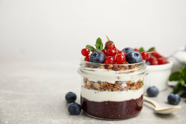 Delicious yogurt parfait with fresh berries and mint on light grey table, space for text - 写真・画像