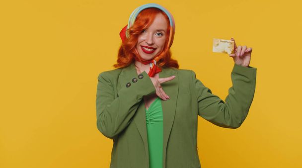 Рыжая молодая женщина показывает пластиковые кредитные банковские карты реклама передачи денег безналичных покупок онлайн покупки, продажа скидка интернет-заказ доставки покупки. Рыжая девушка на жёлтом фоне - Фото, изображение