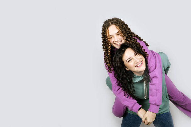 Studio Portrait of happy family mom and teenager daughter spend time together. Teenage girl with her mother having fun together - Photo, Image