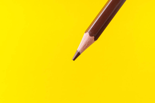 Colored pencil close-up with selective focus on the stylus and a blurred yellow background. Copy space for text. - Fotó, kép