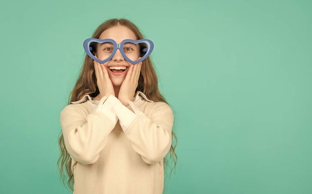 fancy party look. happy funny kid in glamour eyeglasses on blue background. funky teen girl having fun. glad child in party glasses. fashion accessory. going crazy. childhood happiness. - Photo, image