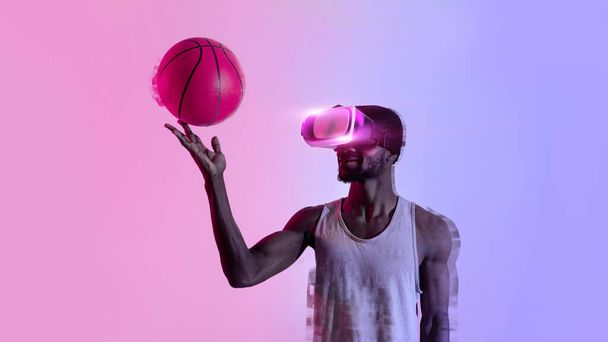 Millennial black basketballer playing with ball in virtual reality headset, neon lighting. Fit athlete using modern VR technologies to train for game competition, panorama with bank space, collage - Foto, afbeelding