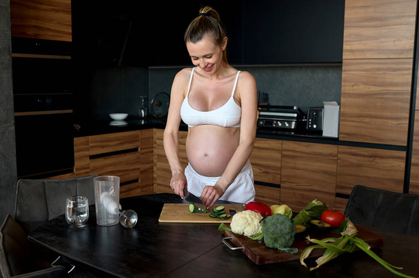 Beautiful pregnant woman making fruits smoothies with blender. Healthy pregnant eating lifestyle concept - Φωτογραφία, εικόνα