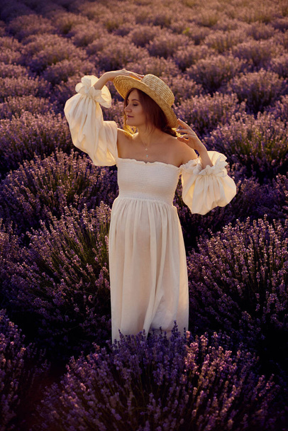 the pregnant girl with a hat in the lavender field on a sunset - Foto, imagen