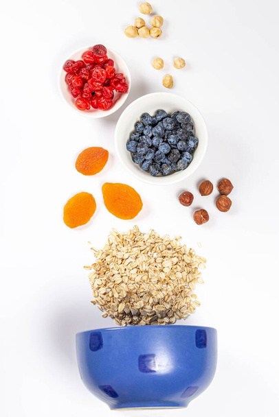 Blue bowl with raw oatmeal, dried berries and nuts, top view - Foto, afbeelding