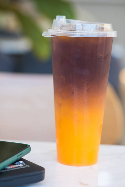 Оранжева американська кава з льодом у чашці для забирання. крупним планом
 - Фото, зображення