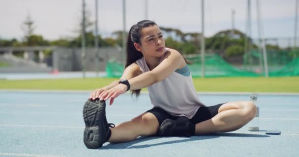 Fit woman warming up legs and stretching prevent injury and prepare for a workout on a sports track. Focused young latino athlete preparing her body and muscles for a cardio training and exercise. - Metraje, vídeo