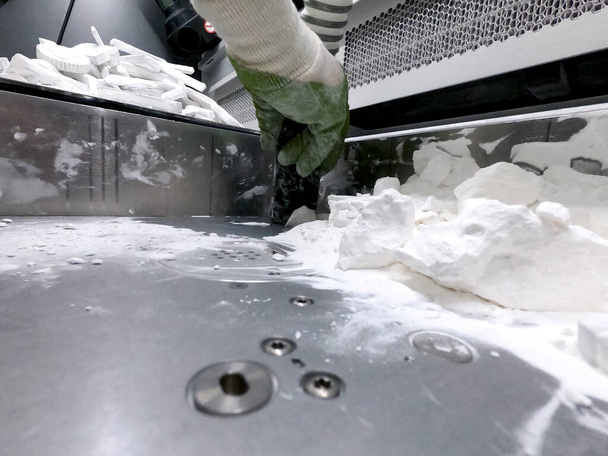 A man working with a working vacuum cleaner to clean the white powder of polyamide from a model printed on a 3D printer inside a 3D printer. Cleaning objects printed on an industrial powder 3D printer - Photo, Image